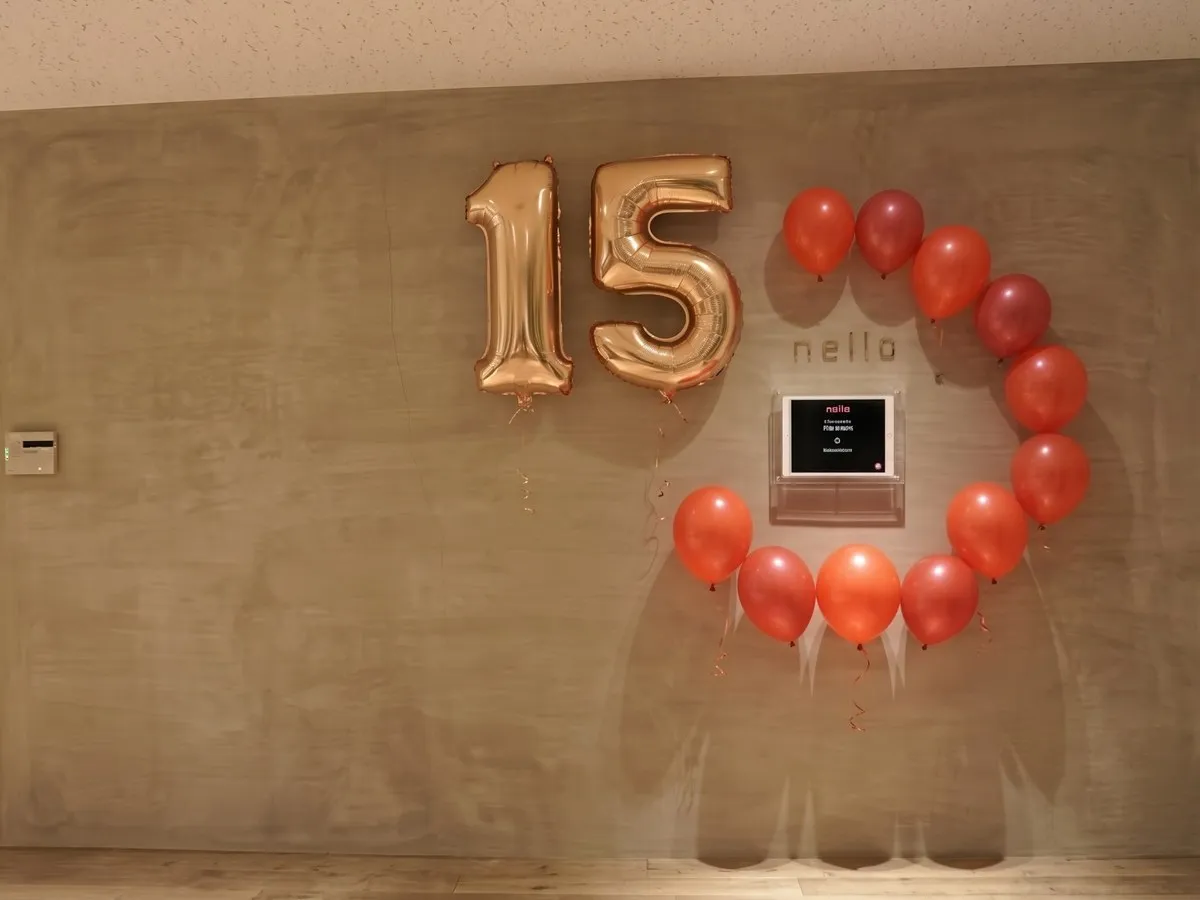 創業15周年の飾りつけをしたエントランス。壁に「15」の風船と赤い風船の輪